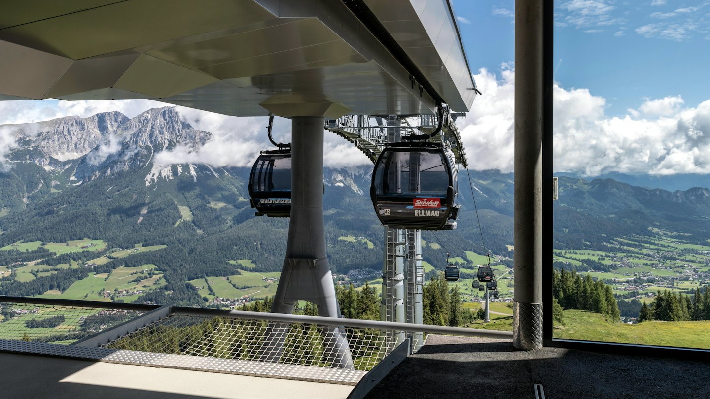 Moderne funivie in una stazione montana con vista sulla valle e sulle montagne rocciose.