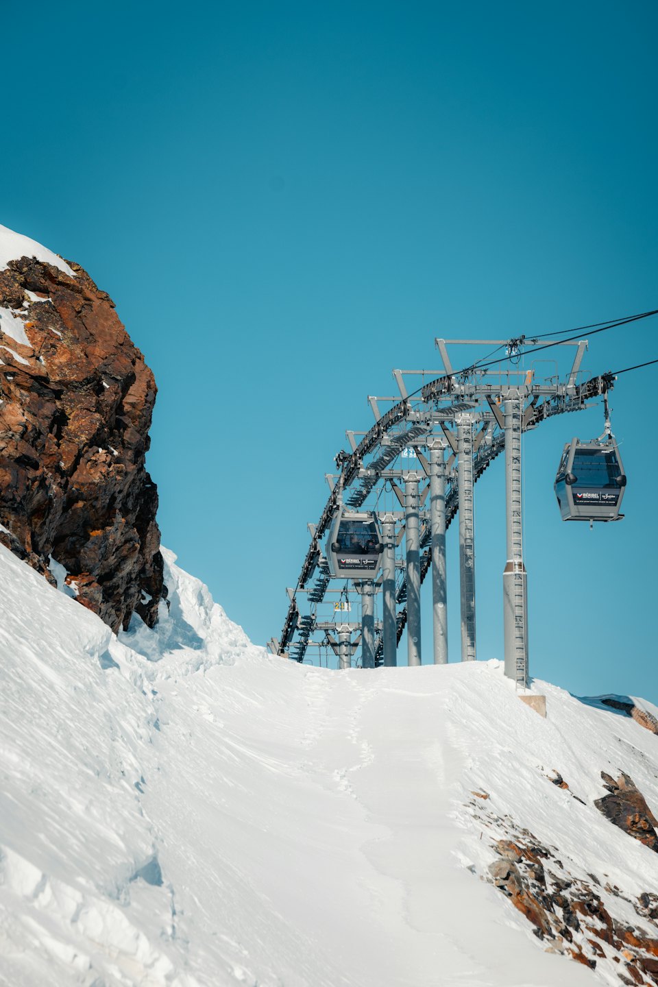 Le cabine della funivia salgono su una montagna innevata verso la vetta.